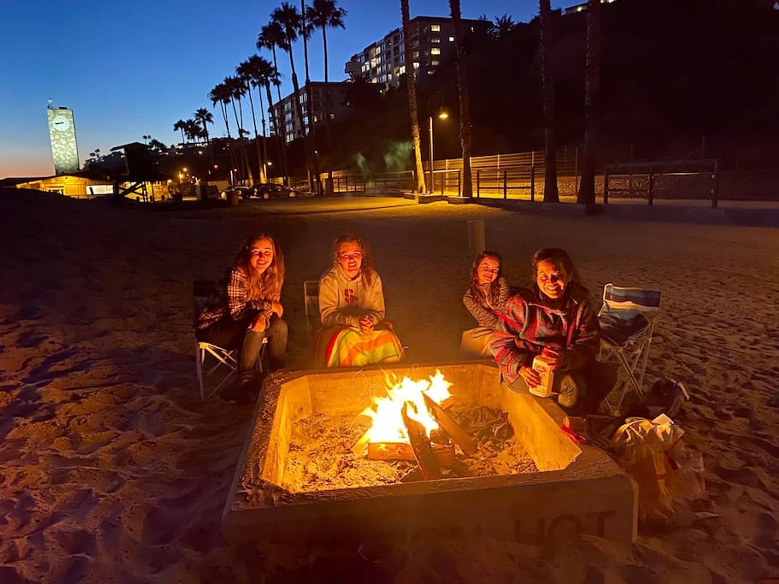 The family around a fire ring on the beach at dusk